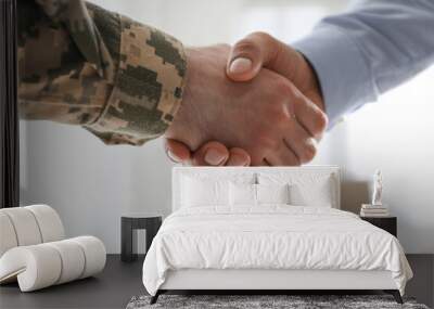 Soldier and businessman shaking hands indoors, closeup Wall mural