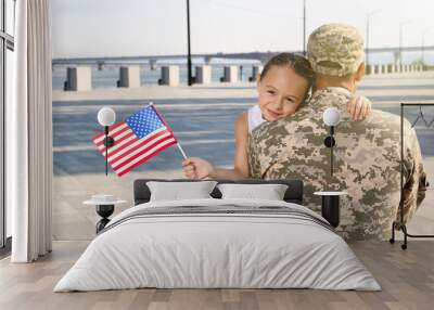 Soldier and his little daughter with flag of USA hugging outdoors Wall mural