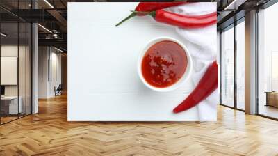 Spicy chili sauce in bowl and fresh peppers on white wooden table, flat lay. Space for text Wall mural