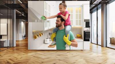 Spring cleaning. Father and daughter tidying up in kitchen together Wall mural