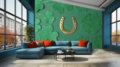 St. Patrick's day. Golden horseshoe and decorative clover leaves on green background, flat lay Wall mural