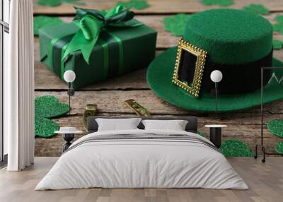 St. Patrick's day. Leprechaun hat, golden horseshoe, green gift box and decorative clover leaves on wooden background Wall mural