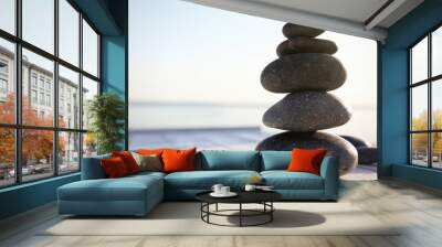 Stack of dark stones on wooden deck near sea. Zen concept Wall mural