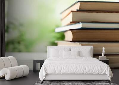 Stack of hardcover books on wooden table against blurred background, closeup. Space for text Wall mural