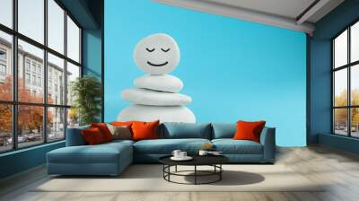 Stack of stones with drawn happy face on light blue background, space for text. Zen concept Wall mural