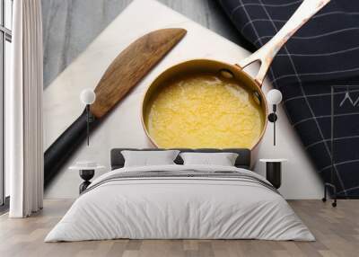 Stone board with saucepan of clarified butter and knife on table Wall mural