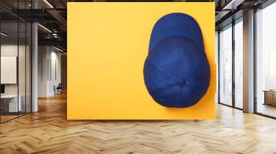 Stylish blue baseball cap on yellow background, top view. Space for text Wall mural