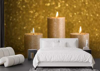 Stylish burning candles on gold shining background Wall mural