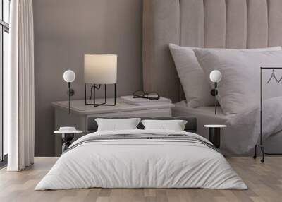 Stylish lamp, notebooks and glasses on bedside table indoors. Bedroom interior elements Wall mural