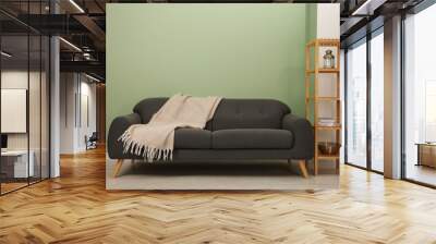 Stylish sofa with blanket and shelving unit near green wall indoors Wall mural