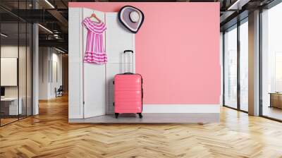 Suitcase near wooden screen with dress and hat indoors. Space for design Wall mural