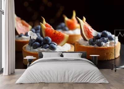 Tarts with blueberries and figs on black table against dark background, closeup. Delicious pastries Wall mural