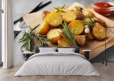 Tasty baked potato and aromatic rosemary served on wooden board, closeup Wall mural