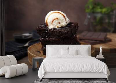 Tasty brownies served with ice cream and caramel sauce on wooden table, closeup Wall mural