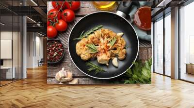 Tasty cauliflower steak in frying pan and other products on wooden table, top view Wall mural