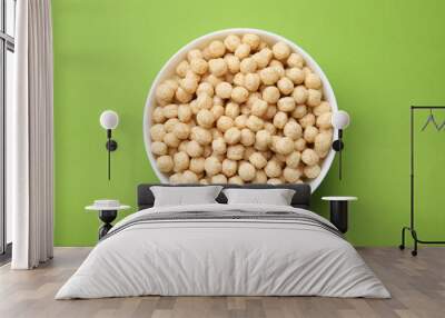 Tasty cereal balls in bowl on green table, top view Wall mural