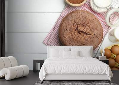 Tasty chocolate sponge cake, whisk and ingredients on white wooden table, flat lay. Space for text Wall mural