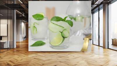 Tasty fresh cucumber water with sliced lime and basil on white table indoors Wall mural