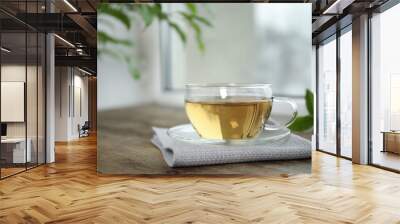 Tasty hot green tea in cup on wooden table Wall mural