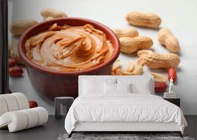 Tasty peanut butter in bowl and groundnuts on white table, closeup Wall mural