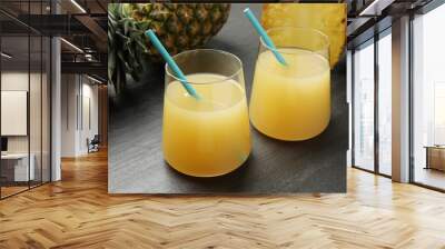 Tasty pineapple juice in glasses and fruits on grey textured table, closeup Wall mural