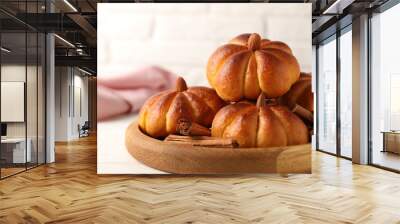 Tasty pumpkin shaped buns and cinnamon sticks on white table, closeup Wall mural