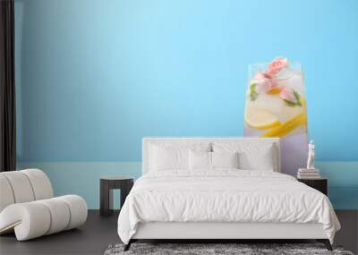 Tasty refreshing lemon drink with roses on wooden table against light blue background. Space for text Wall mural