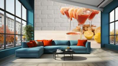 Tasty shrimp cocktail with sauce in glasses and lemon on light wooden table, space for text Wall mural