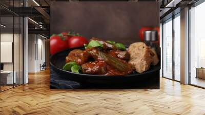 Tasty stew with okra, tomato sauce, bread and basil on wooden table, closeup Wall mural