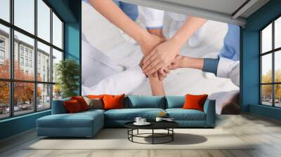 Team of medical doctors putting hands together indoors, above view Wall mural