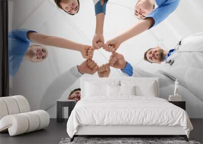 Team of medical doctors putting hands together indoors, bottom view Wall mural