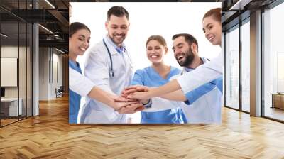 Team of medical doctors putting hands together on white background. Unity concept Wall mural