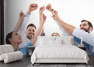 Team of medical doctors raising hands together on white background. Unity concept Wall mural