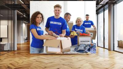 Team of volunteers collecting donations in boxes indoors Wall mural