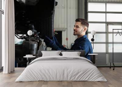 Technician checking car on hydraulic lift at automobile repair shop Wall mural