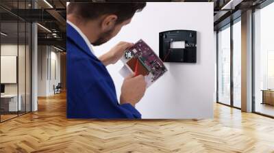 Technician installing home security alarm system on white wall indoors Wall mural