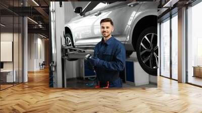 Technician with tool in automobile repair shop Wall mural