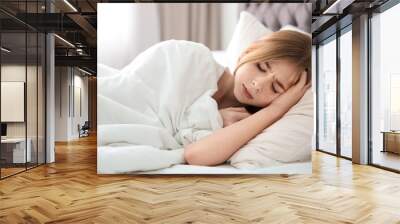 Teenage girl suffering from headache while lying in bed at home Wall mural