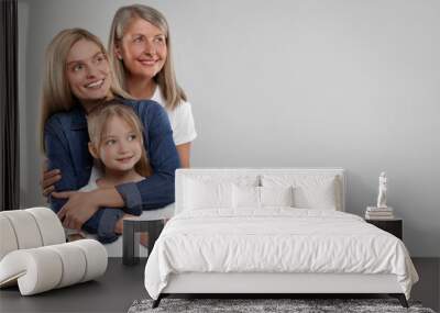 Three generations. Happy grandmother, her daughter and granddaughter on light gray background, space for text Wall mural