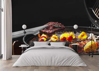 Tongs with tasty steak near modern barbecue grill Wall mural