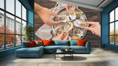 Top view of people with fresh oysters at table, focus on hands Wall mural