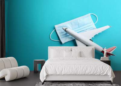 Toy airplane and protective mask on light blue background, flat lay with space for text. Travelling during coronavirus pandemic Wall mural