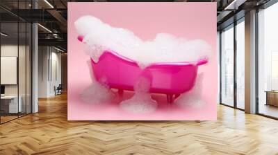 Toy bathtub overflowing with foam on pink background Wall mural