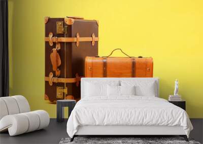 Two different brown suitcases on yellow background Wall mural