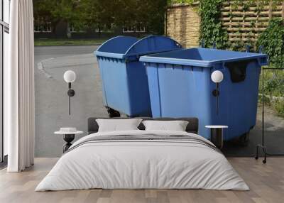 Two open blue dumpsters with wheels on city street Wall mural