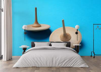 Two wooden spinning tops on light blue background Wall mural