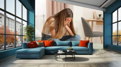 Unhappy teenage girl covering face with hands on bed at home Wall mural