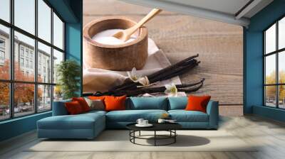 Vanilla pods, sugar in bowl and flowers on wooden table, closeup Wall mural