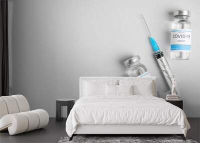 Vials with coronavirus vaccine and syringe on light background, flat lay. Space for text Wall mural