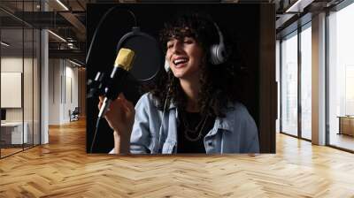 Vocalist with headphones singing into microphone in professional record studio Wall mural